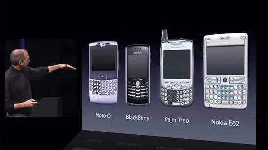 Steve Jobs pointing at the fixed plastic keyboards of the four smartphones